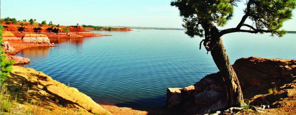 Shore of lake with red rocks and tree